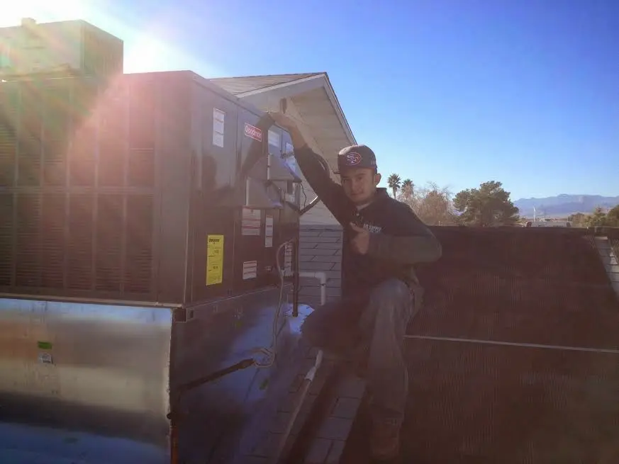 HVAC technician performing AC Tune-Up on a rooftop unit in Brunswick